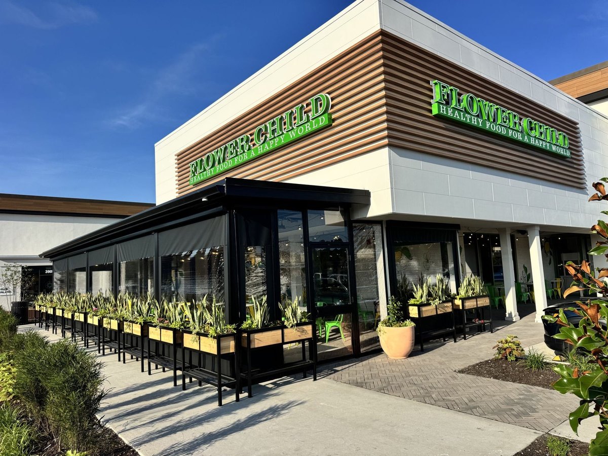 Flower Child's corner patio in Prairie Village, Kansas, enclosed with motorized clear vinyl panels, planters along the front