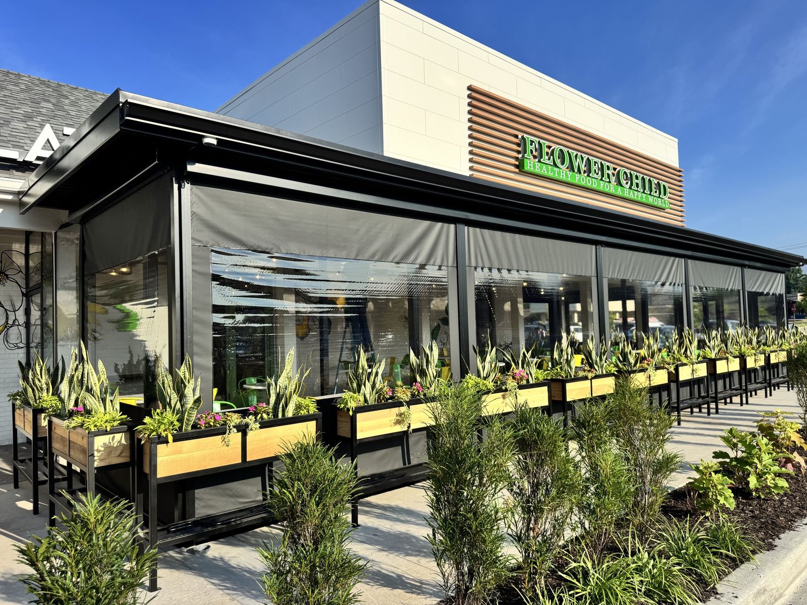 Flower Child in Prairie Village, Kansas: patio enclosed with motorized clear panels, planters along the front
