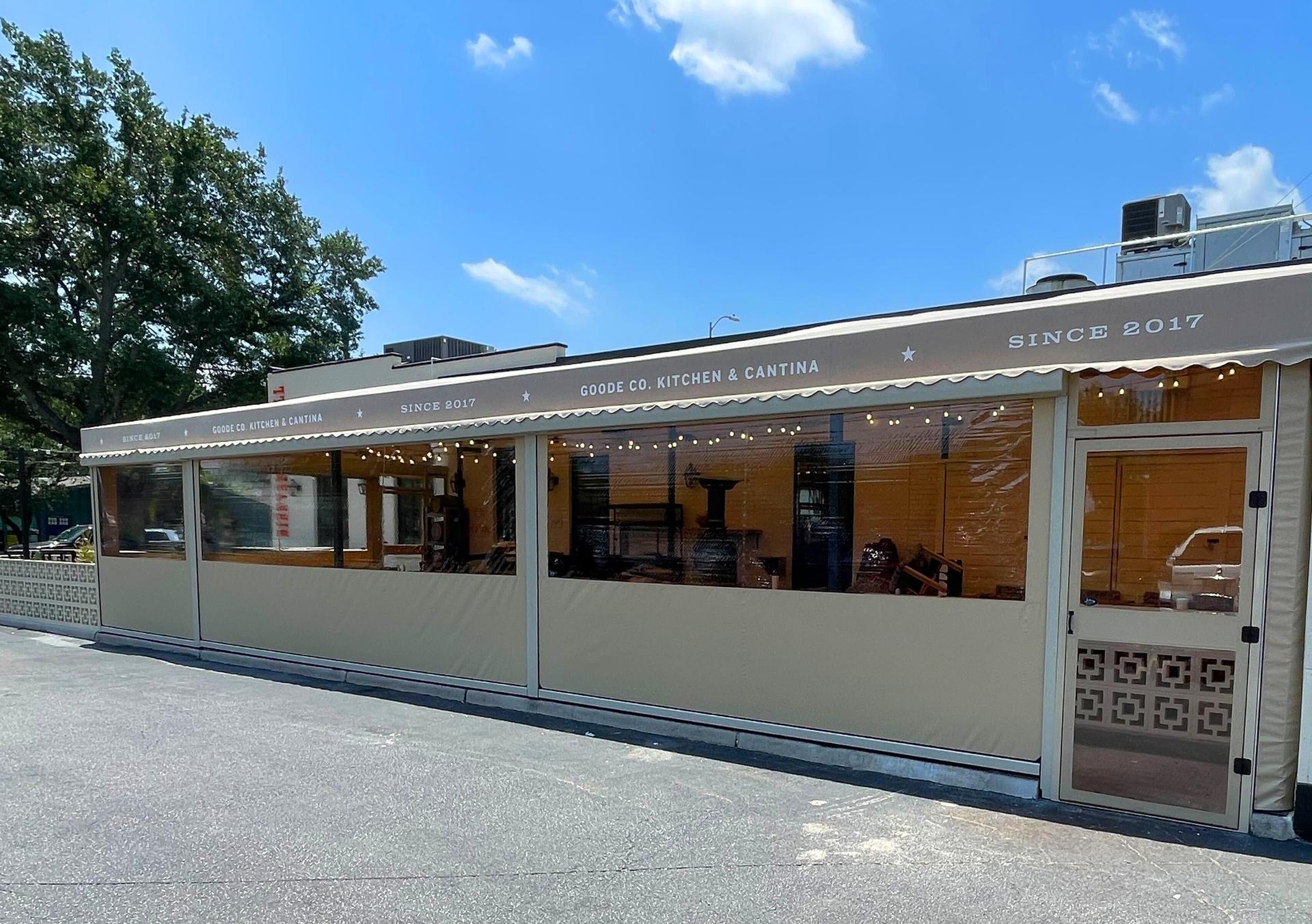 Goode Co. Kitchen & Cantina in Houston, Texas: the patio enclosed with motorized tan panels, clear windows at eye level and a matching door