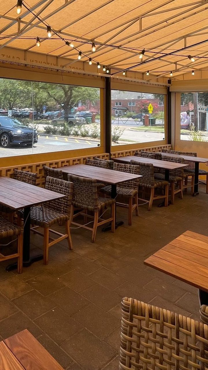 Inside the patio at Goode Co. Kitchen & Cantina in Houston, Texas, enclosed with motorized tan panels, clear windows at eye level, tables set under string lights