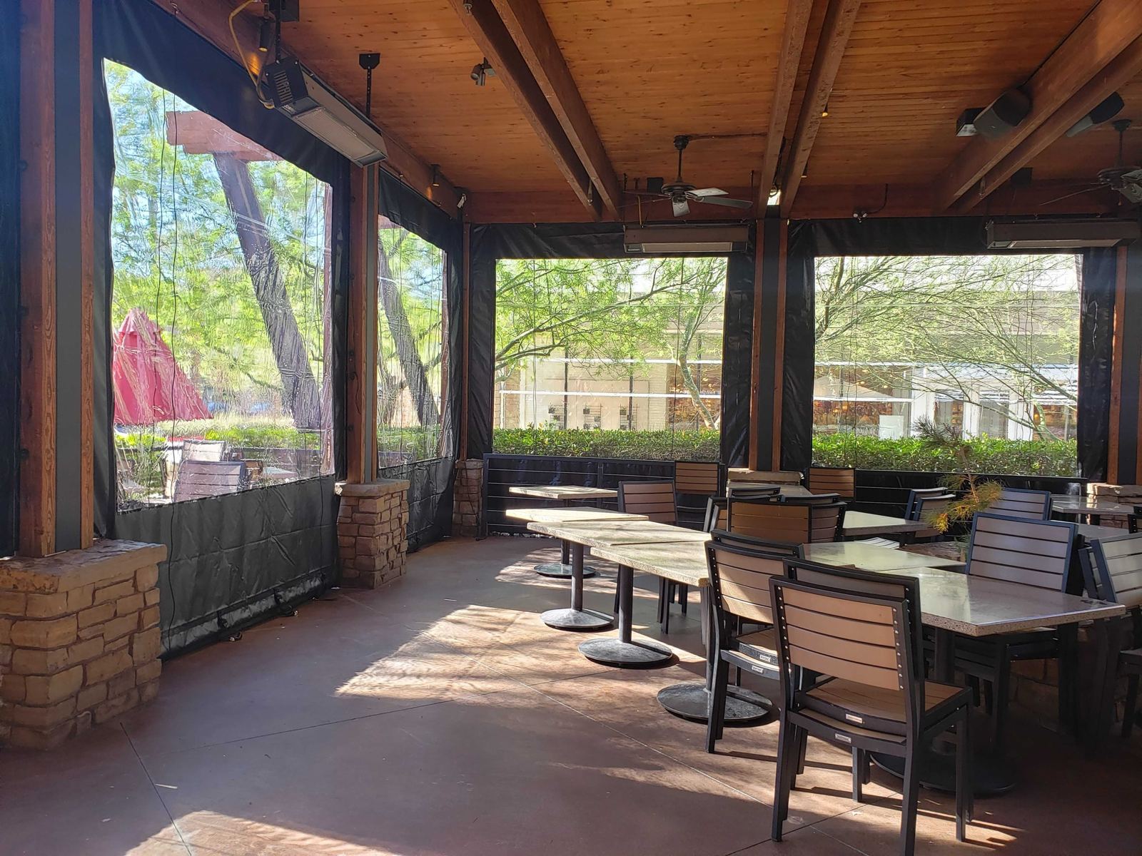 Patio dining area with clear panels down between stone columns