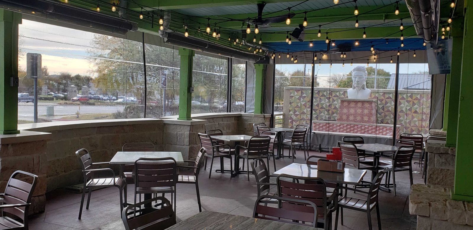 Inside Chuy's Frisco: the clear panels down around the patio, the lights and the disco balls under the green beams