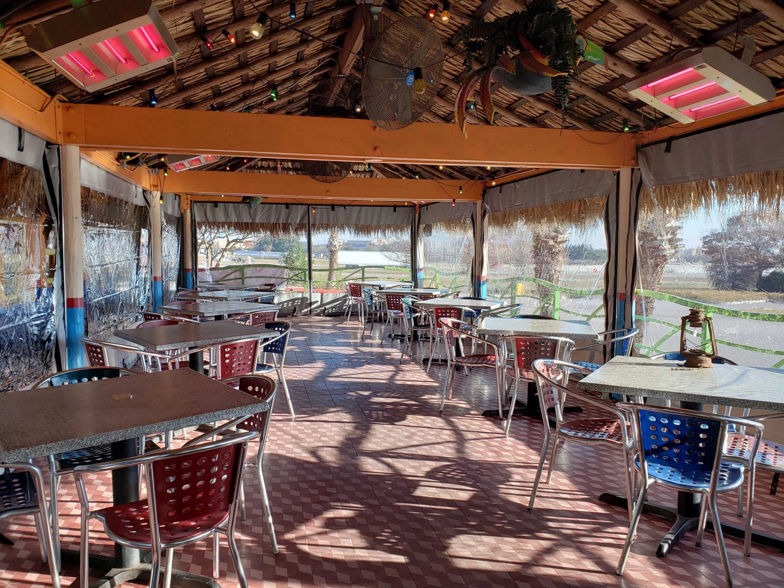 Inside Chuy's Waco under the palapa: heaters on, clear panels closed, the parking lot bright beyond