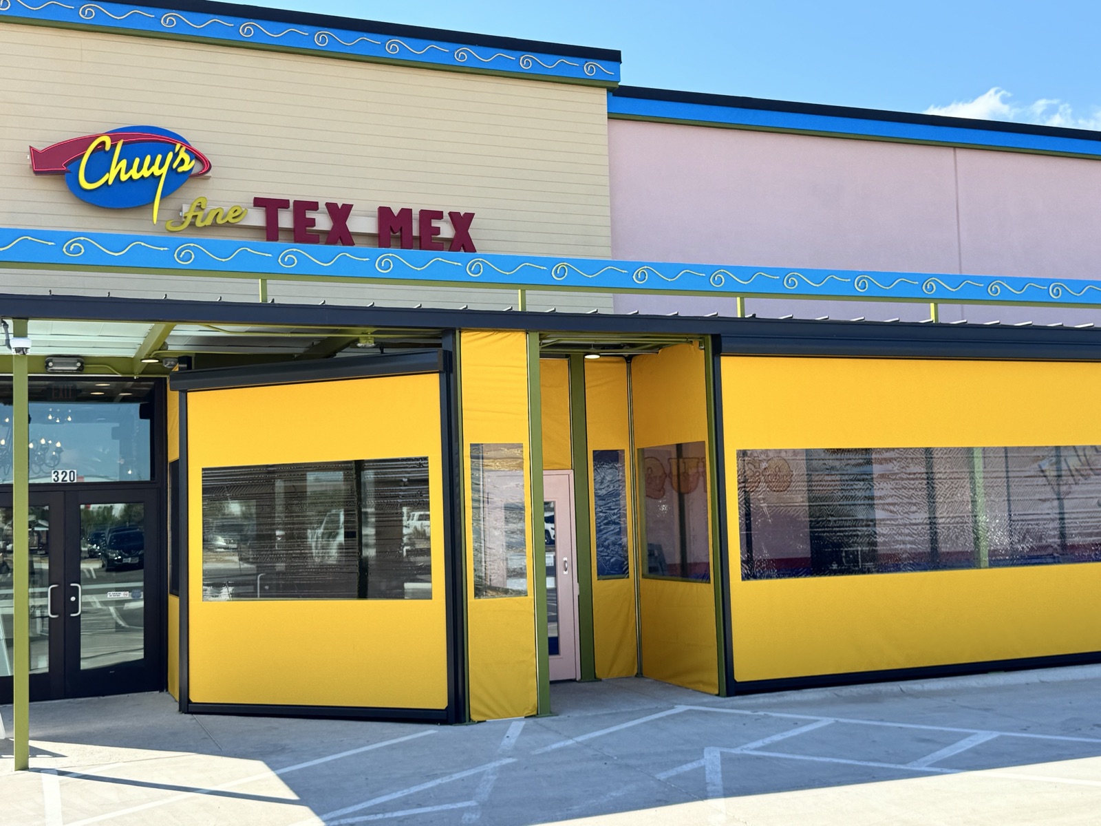 The finished patio from the parking lot, curtains down under the Chuy's sign