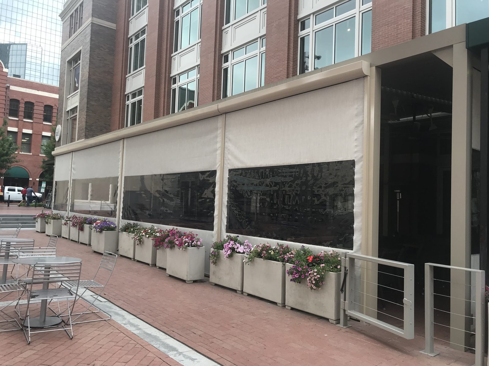 Del Frisco's Grille Fort Worth: tan motorized curtains with clear windows along the Sundance Square patio, planters along the base