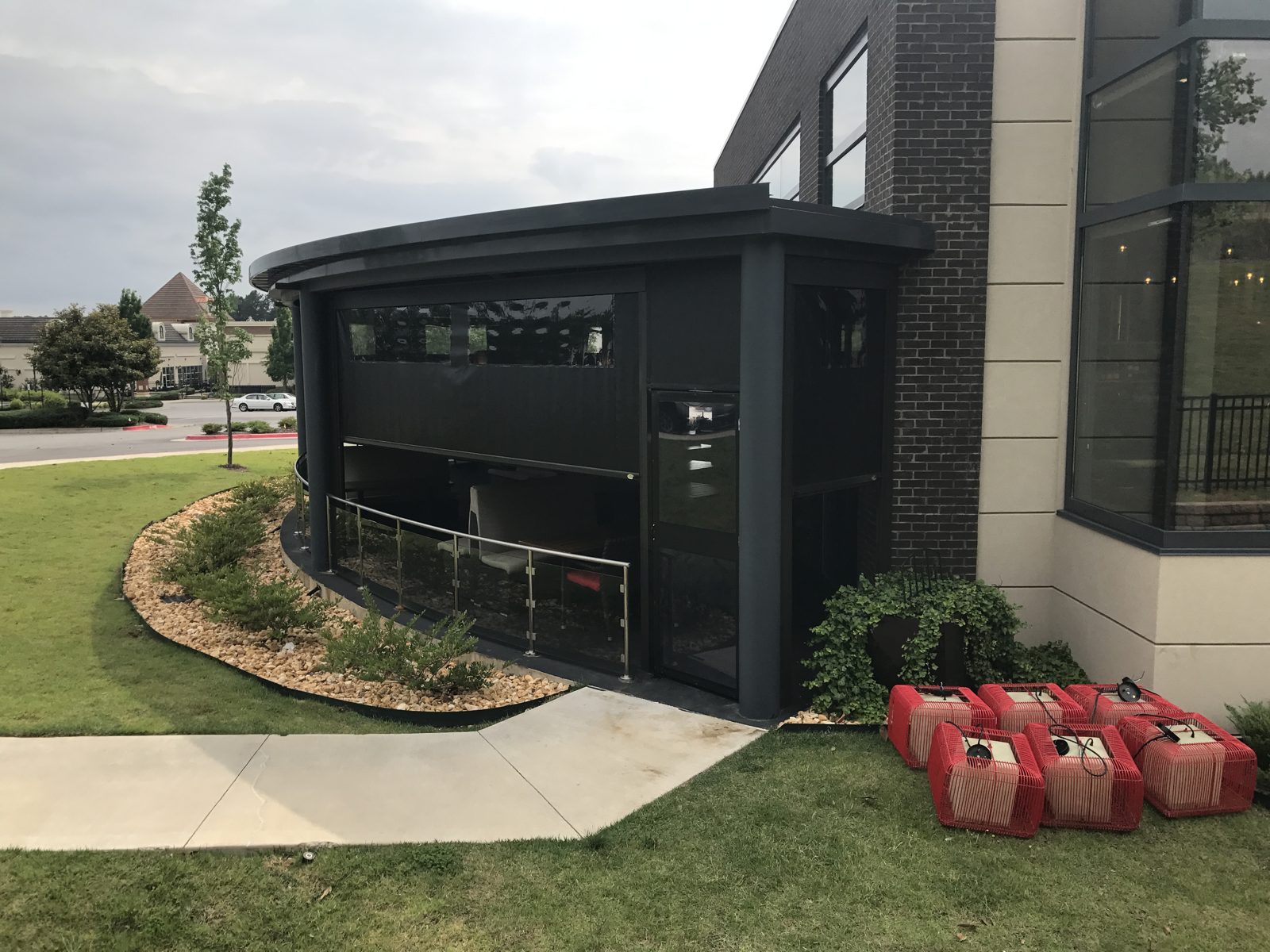 Del Frisco's Little Rock: the curved patio with the black screens up, glass rail and lawn beyond