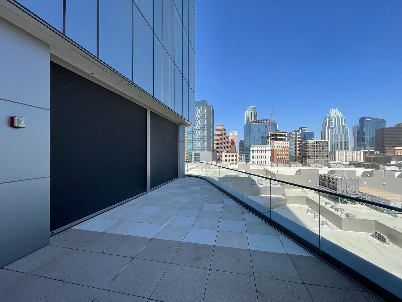 After: a shade down along the outer wall with the glass rail and downtown Austin past it