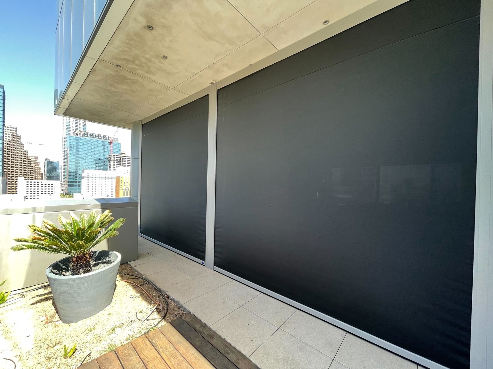 The outer terrace wall from the deck: a shade down, the side track and the city behind it