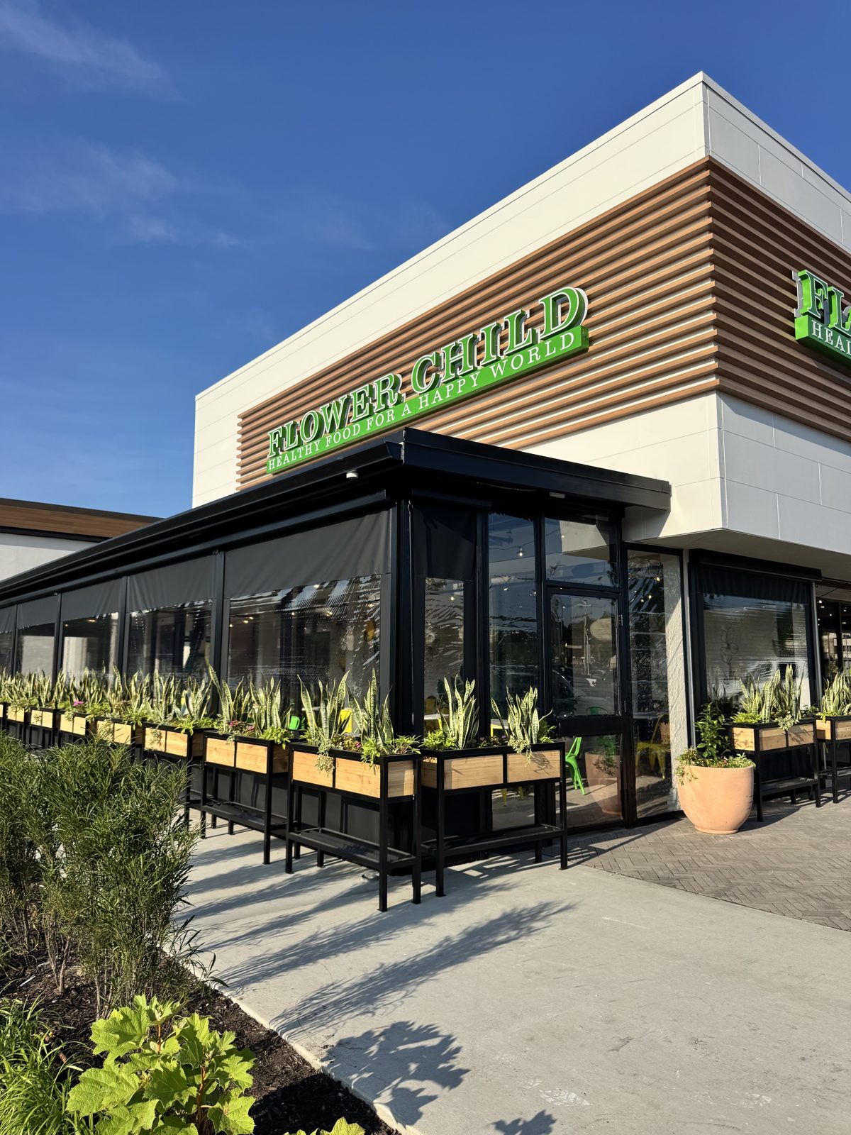 Flower Child Prairie Village: the corner of the patio with the gray screen and clear window, the planters and the entry door