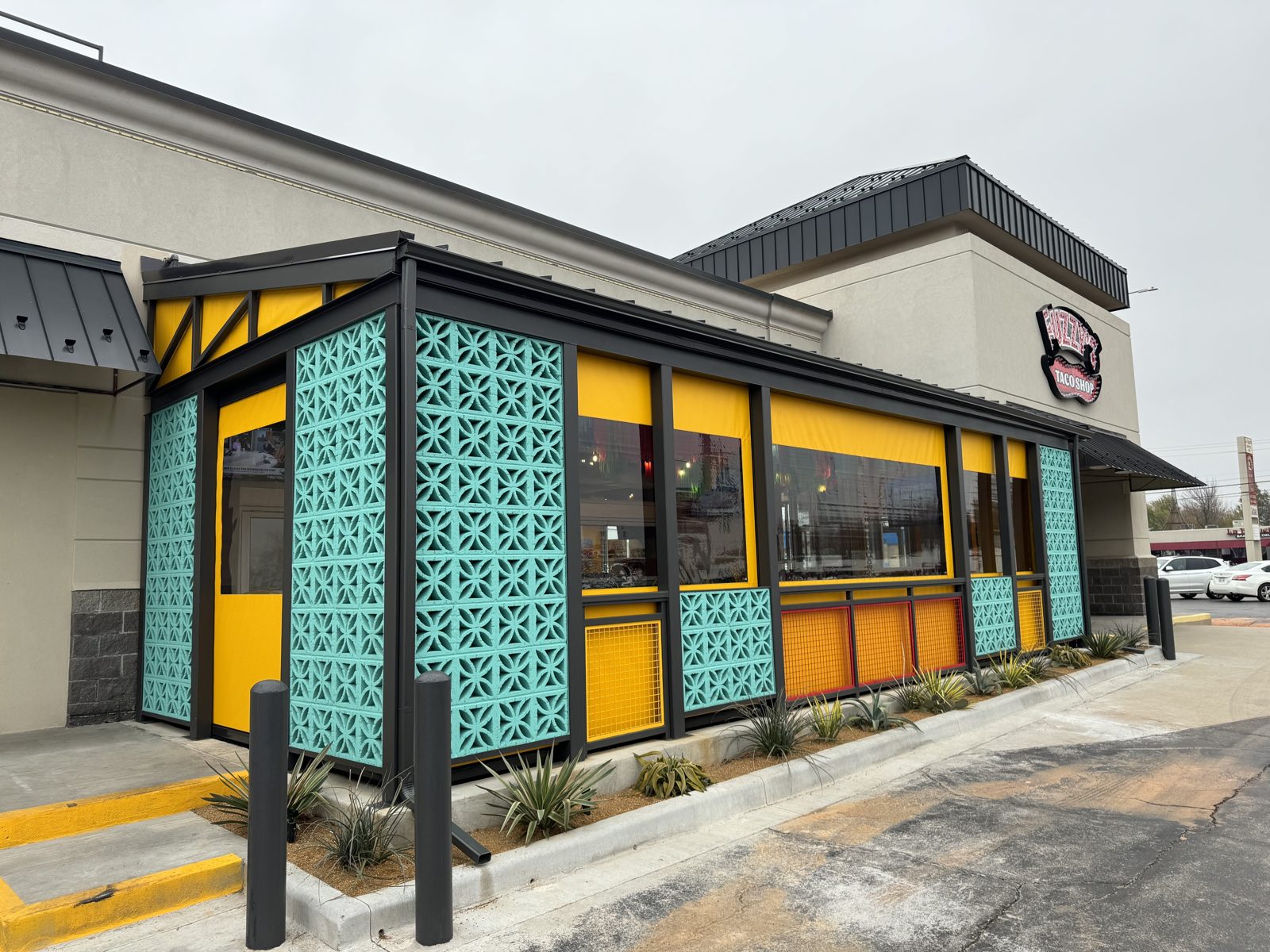 Fuzzy's Taco Shop Oklahoma City: yellow motorized curtains with clear windows set inside the turquoise breeze-block patio wall