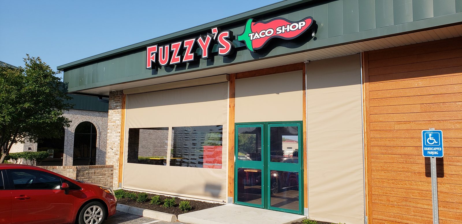 Fuzzy's Columbia, Missouri: tan motorized curtains with clear windows under the sign, the green door at the entry
