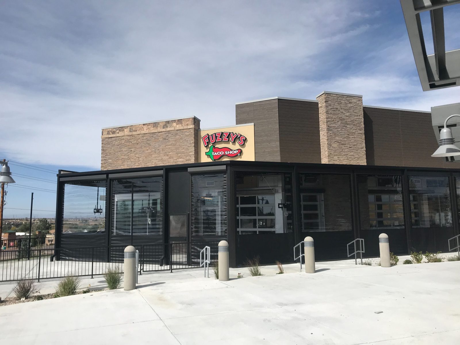 Fuzzy's Parker, Colorado: black motorized curtains with clear windows wrapping the patio under the stone fascia