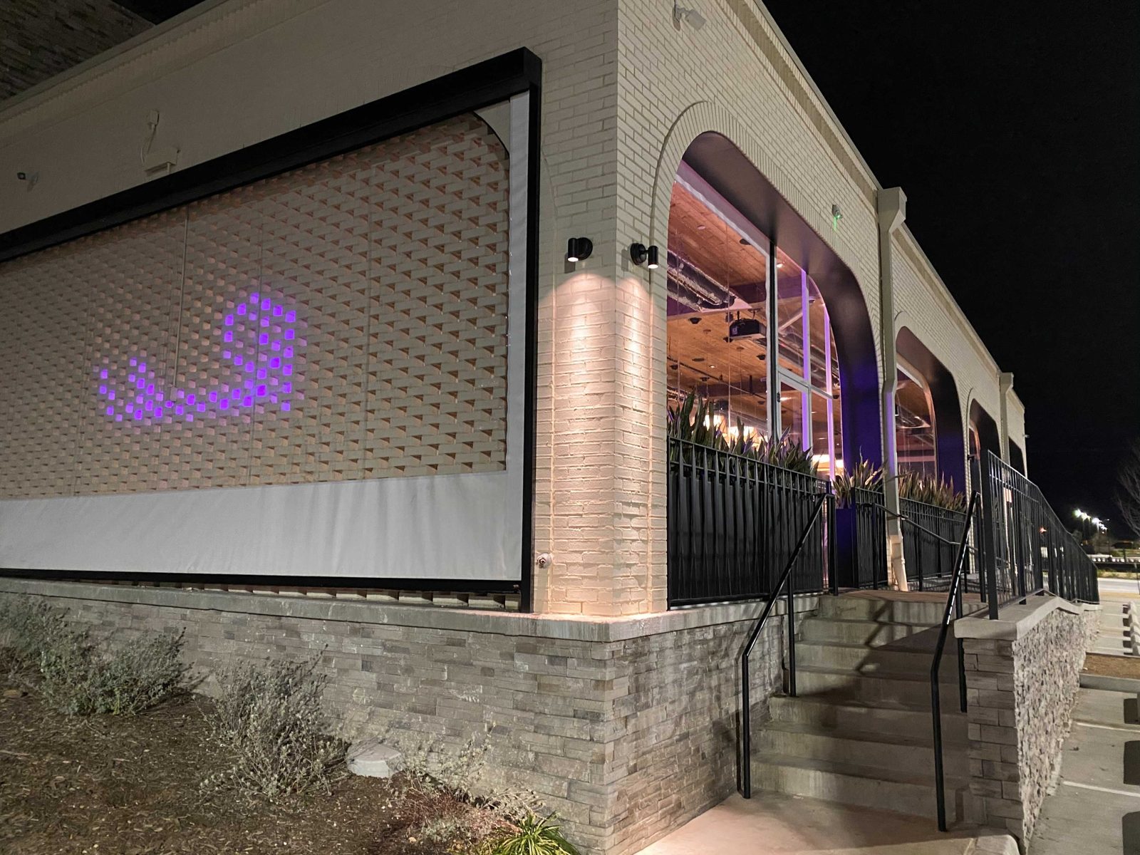 Gloria's McKinney at night: a solid shade lowered over the brick lattice wall, the arched patio lit beside it