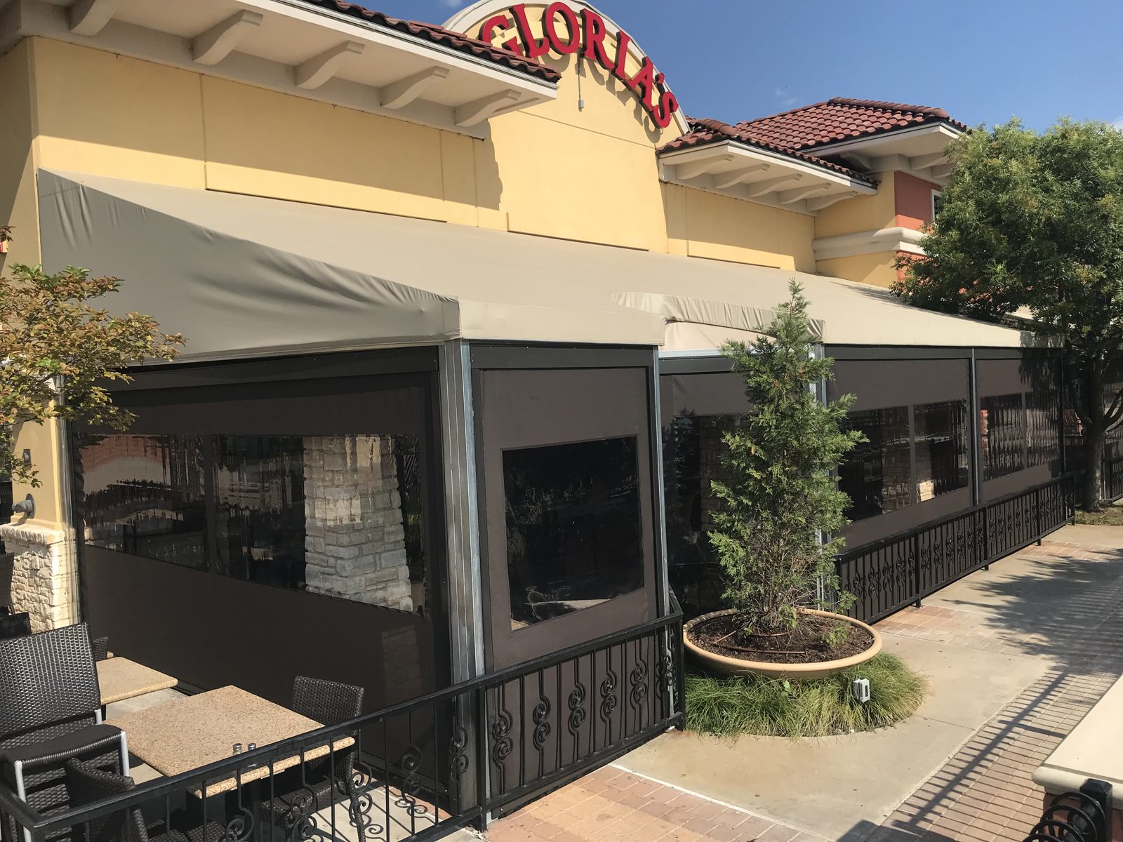 Gloria's Rockwall: dark mesh screens with clear windows under the tan awning and the red-tile roof