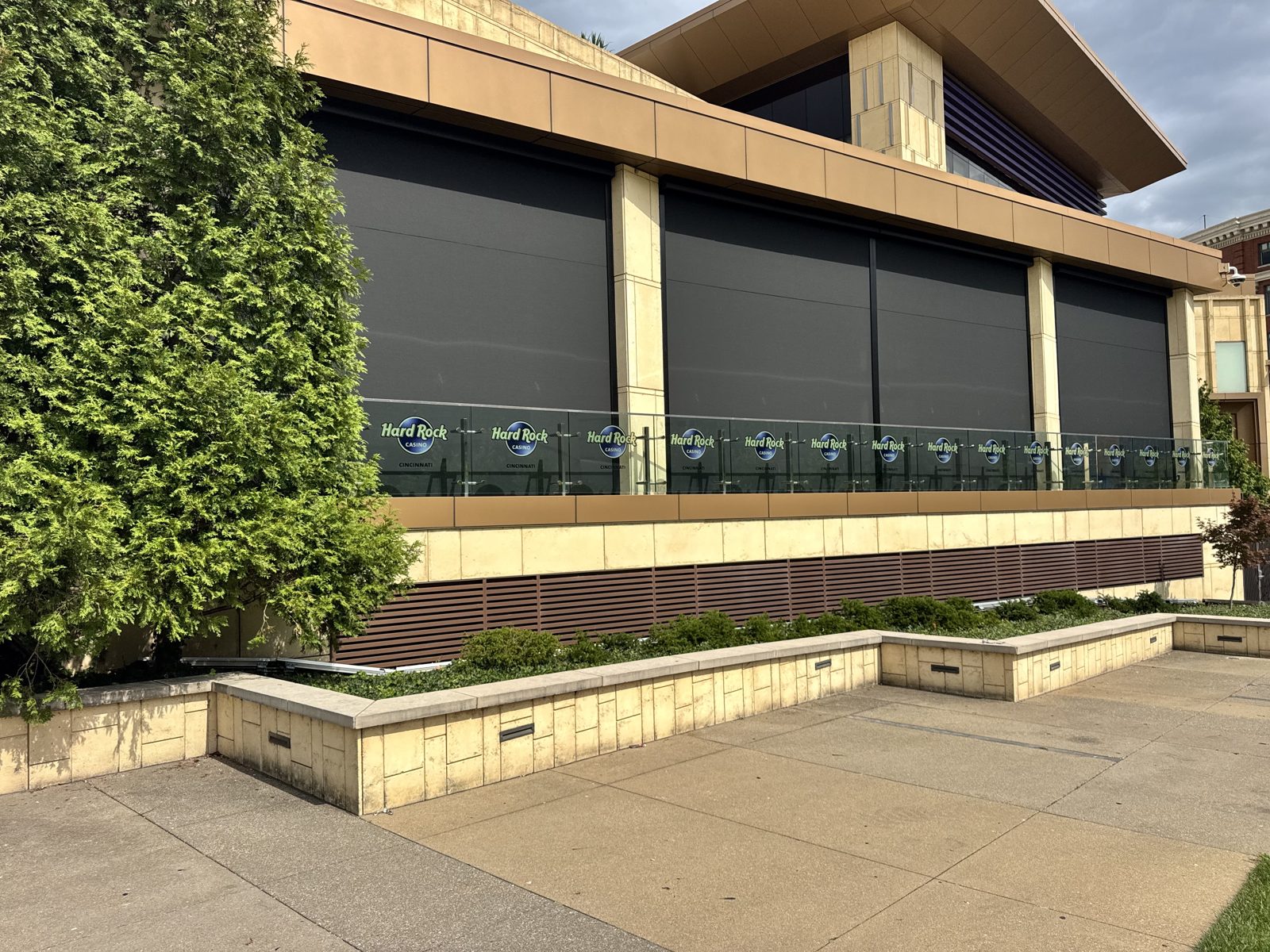 Hard Rock Casino Cincinnati: four motorized sun shades down across the Hard Rock Cafe patio, seen from the lawn