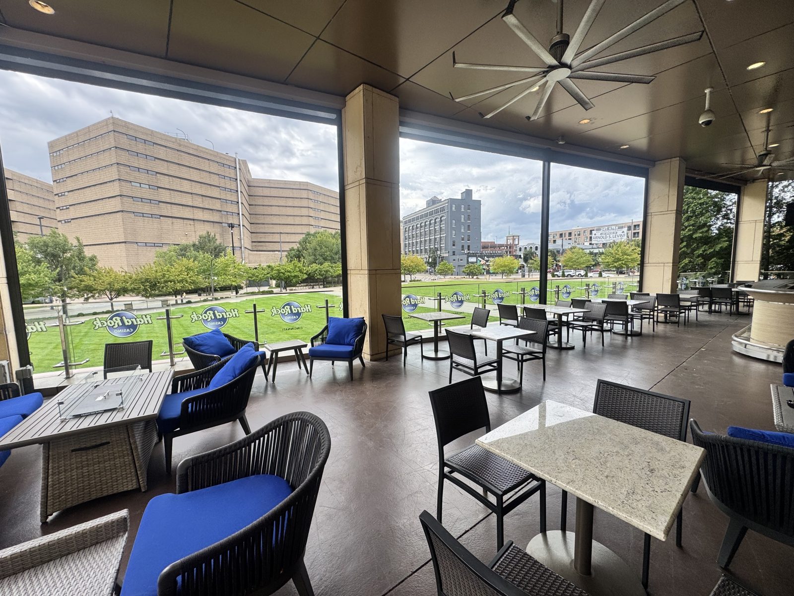 Inside the Hard Rock Cafe patio with the four shades up, the lawn and downtown Cincinnati beyond the glass rail