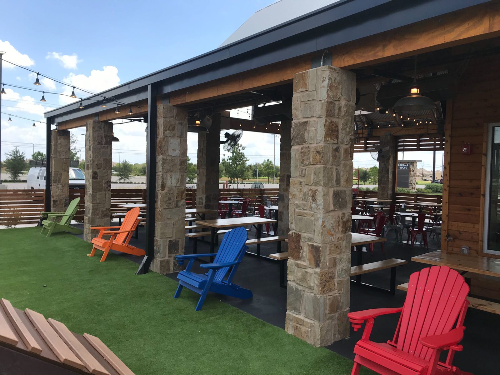 Before: the open Fulshear patio with the Adirondack chairs on the turf and the stone columns, nothing in the openings