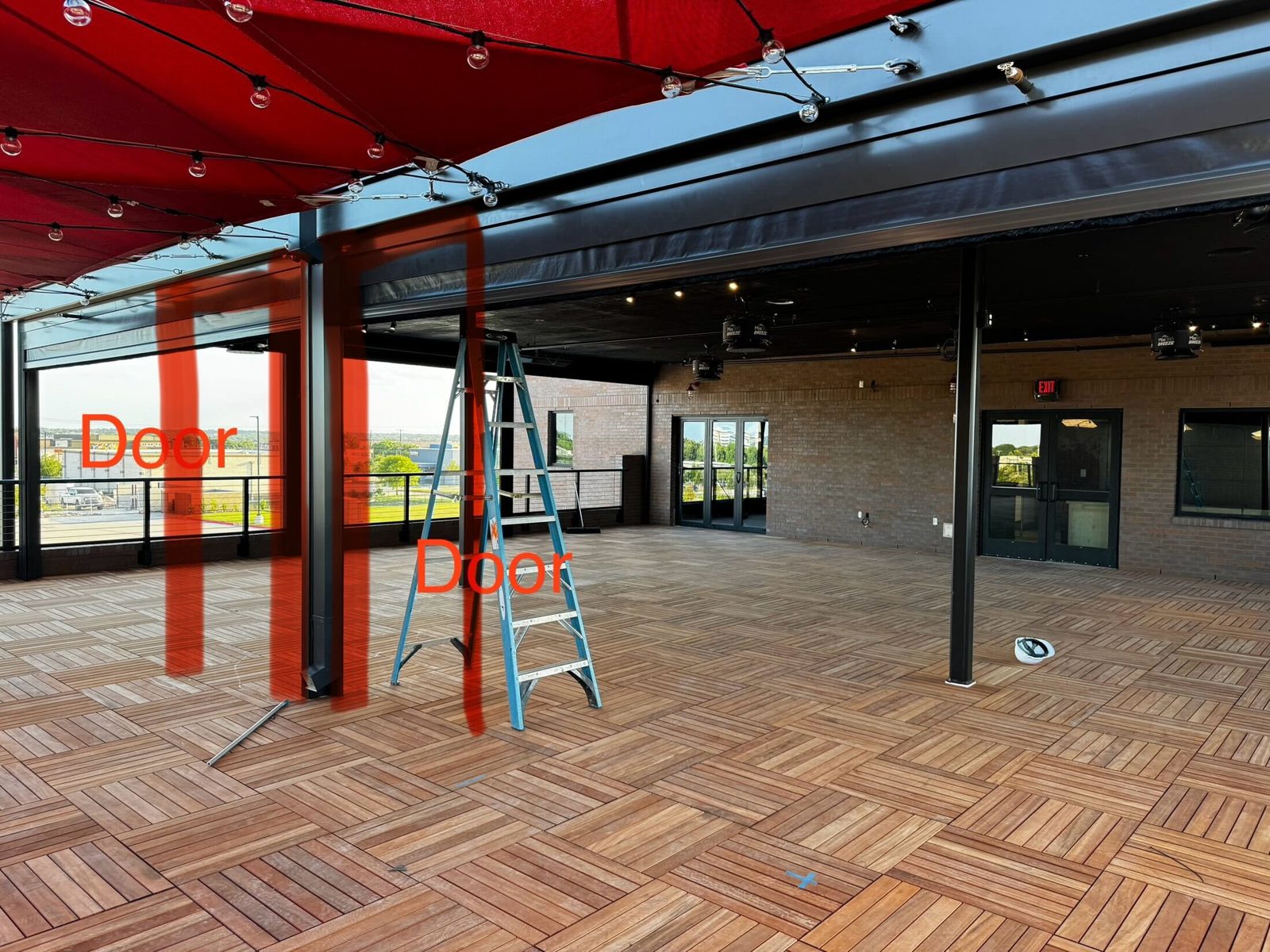Before: the McKinney terrace in build-out, the red sails up, the door positions marked on the steel