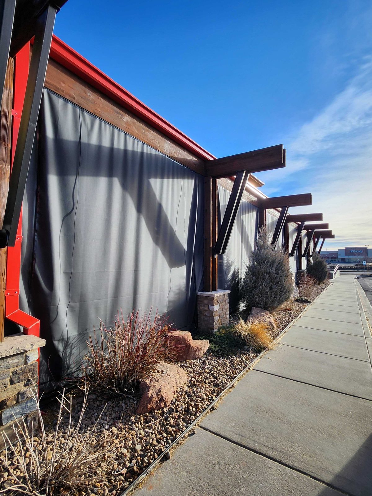 Lazy Dog Aurora, Colorado: gray solid panels down the long side of the patio, the timber brackets casting shadows