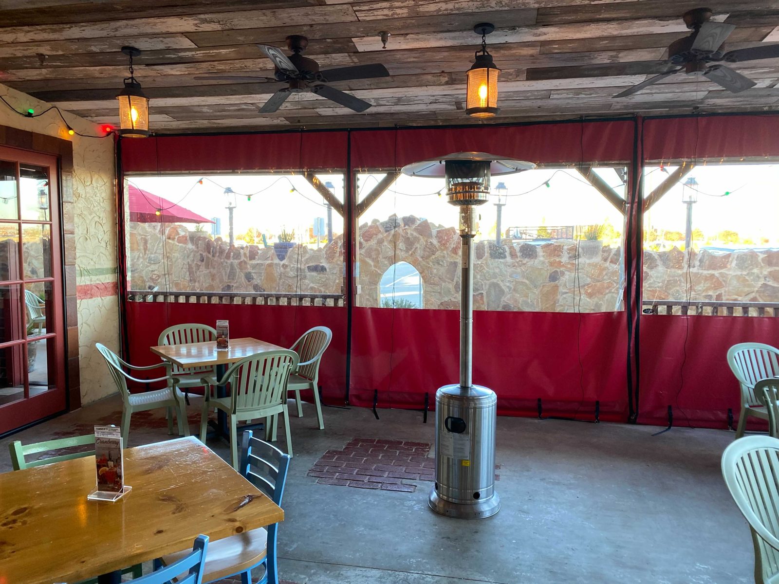 Lupe Tortilla Irving: red and clear panels across the patio opening, the Fiesta banner and the parking lot beyond