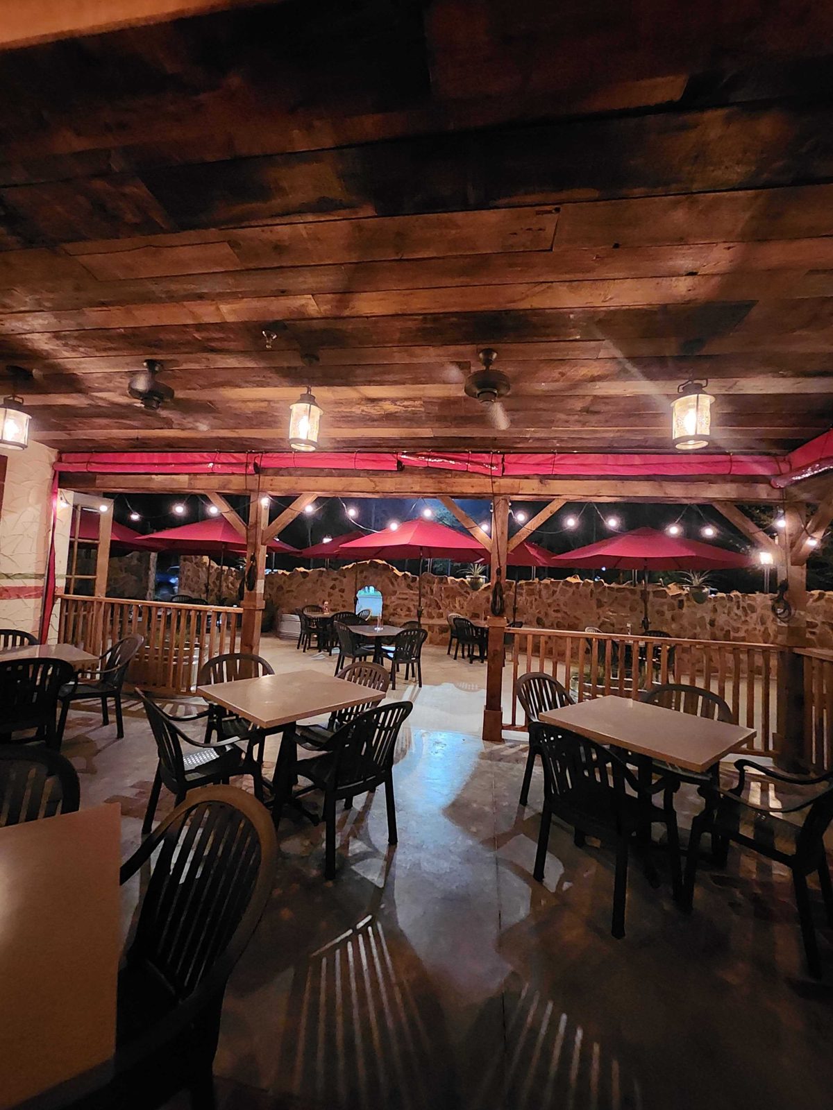 Lupe Tortilla Kingwood at night: red panels down under the lanterns, the stone wall through the clear