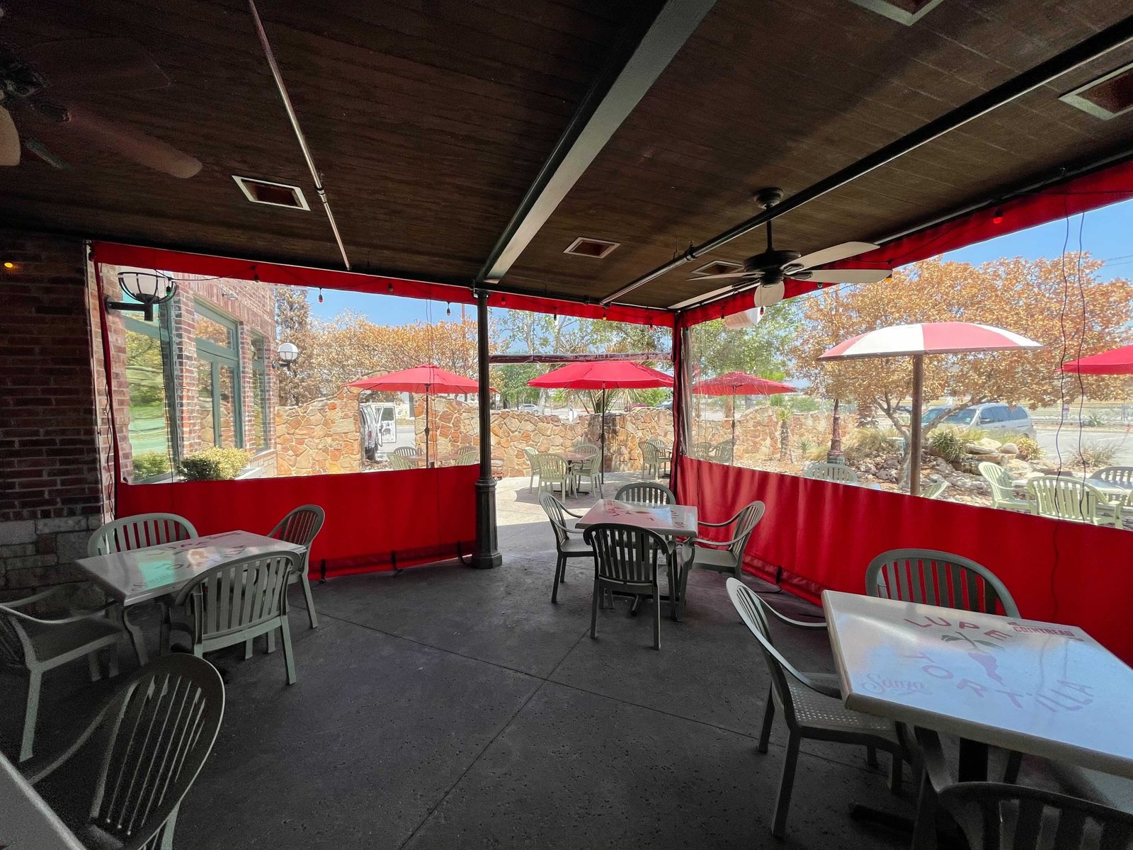 Lupe Tortilla Stone Oak in San Antonio: red and clear panels along the patio with the umbrellas and stone wall beyond