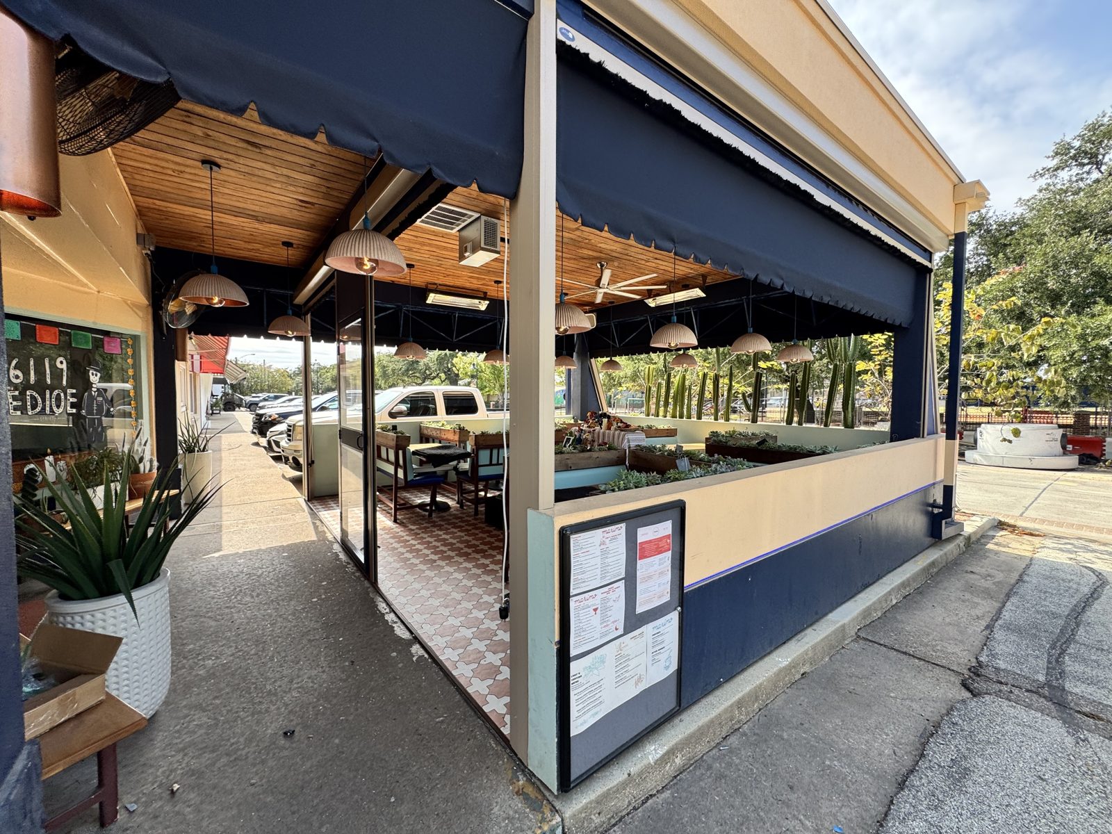 After: the sidewalk side with the framed door open and the long curtain up, lights and planters inside