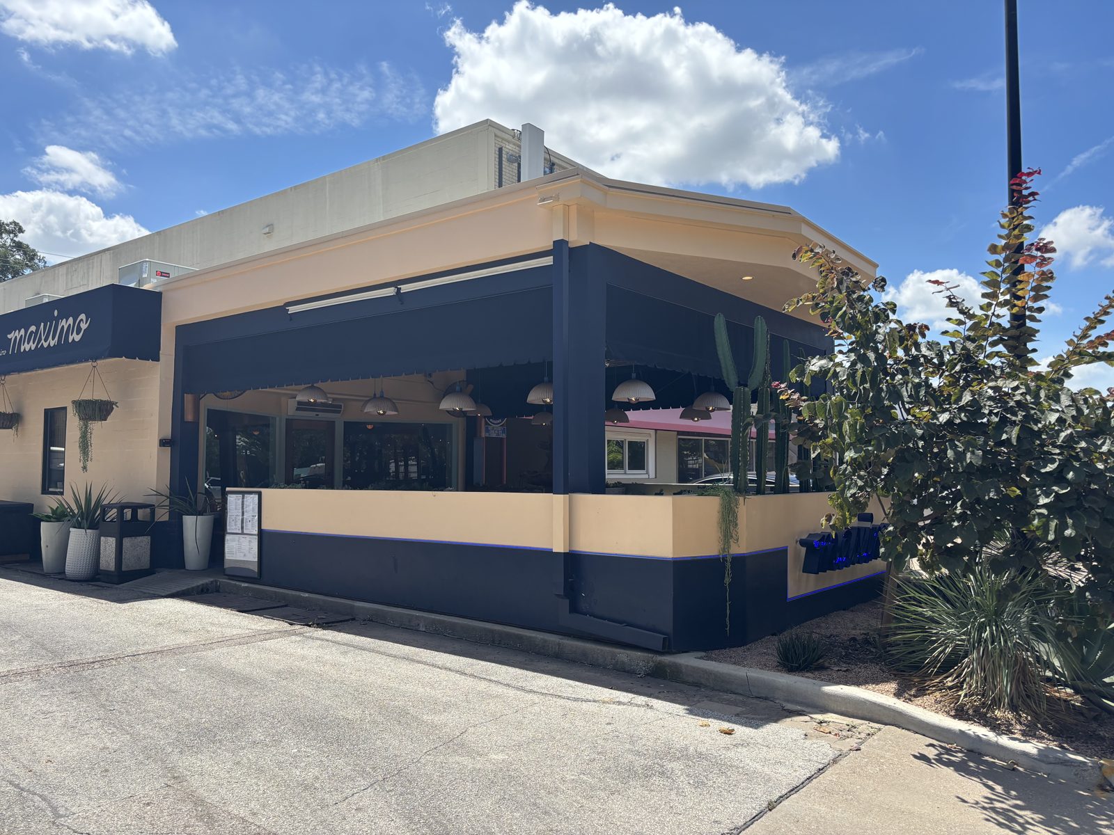 Before: the corner patio in August 2025, the navy awning and open bays to the parking lot