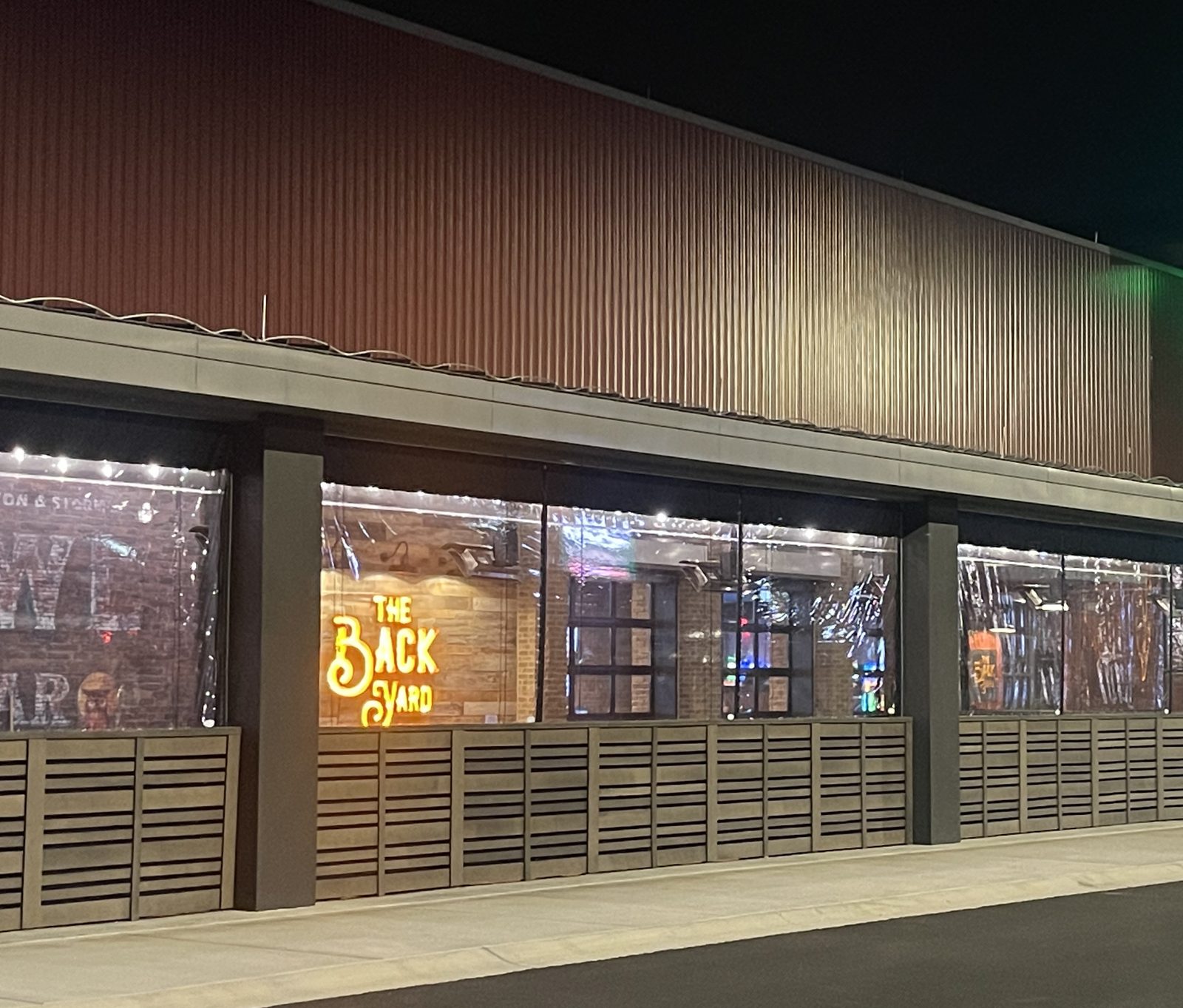 The Back Yard patio at The Mint Gaming Hall Cumberland at night, the manual clear vinyl panels down along the street side