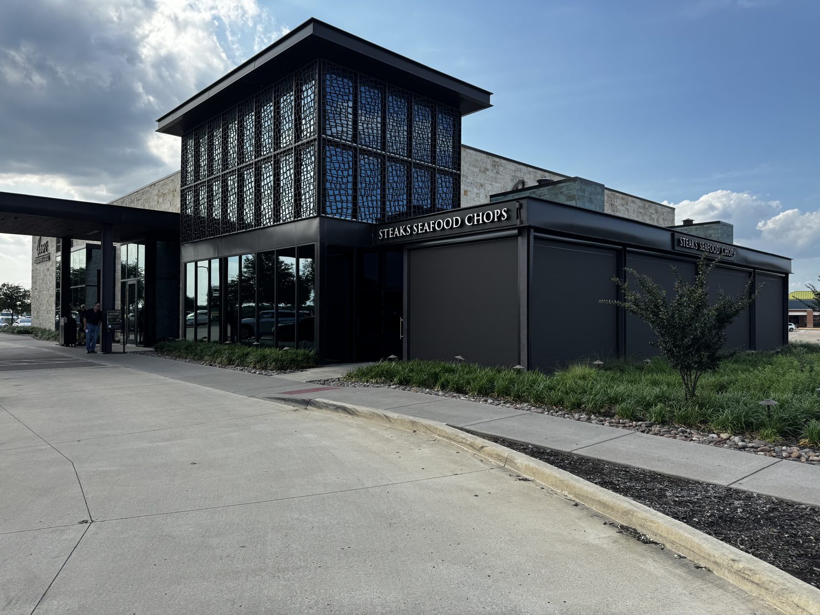 Perry's Steakhouse & Grille, Grapevine: tobacco mesh sun shades down along the patio beside the glass entry tower