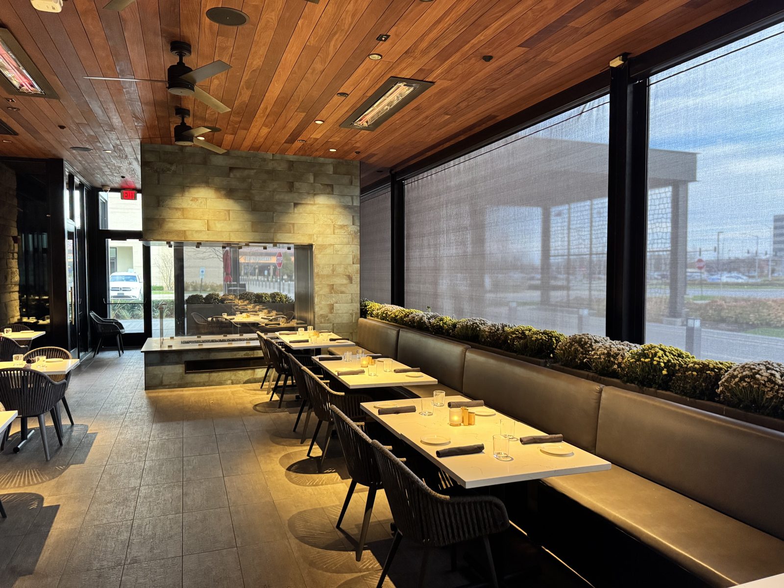 Inside Perry's Schaumburg: the dining room with the mesh down, the parking lot softened to a glow and the tables lit
