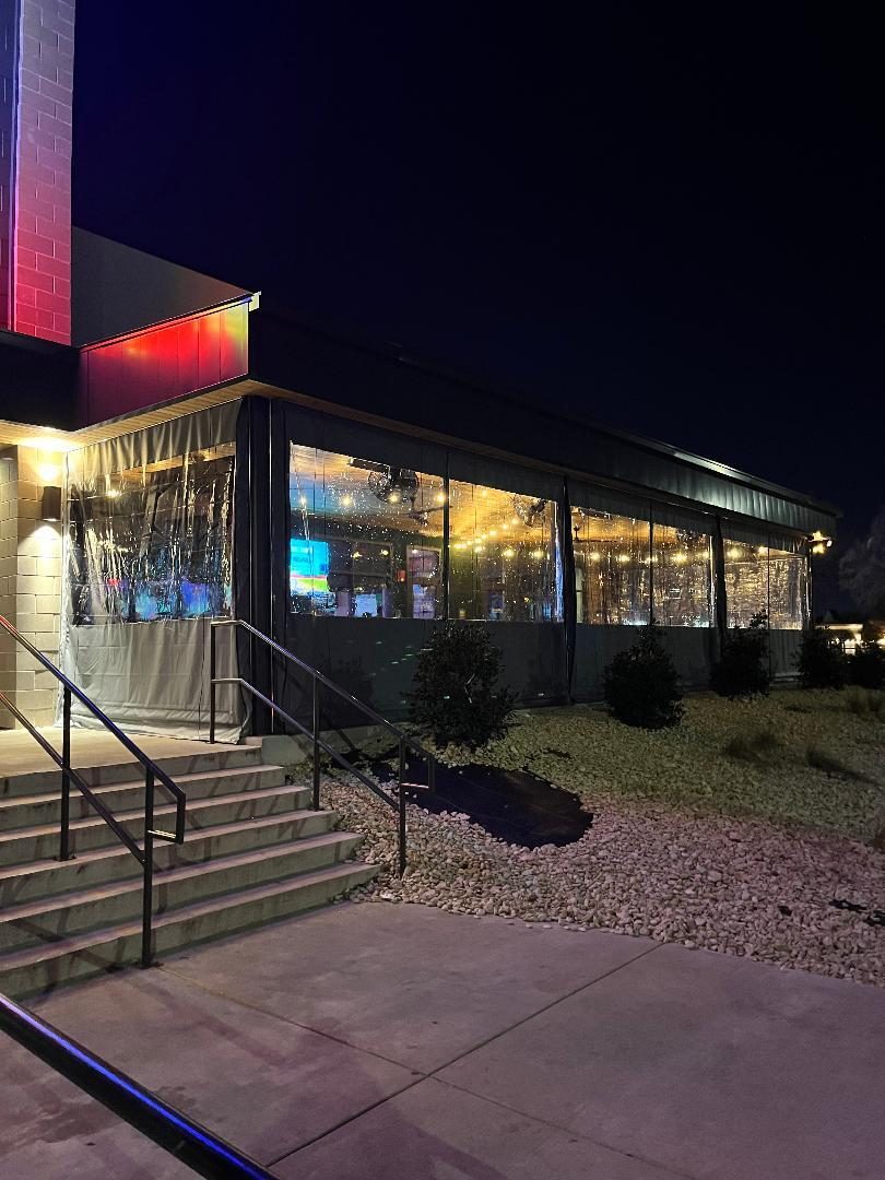 Pluckers Mesquite at night: the charcoal and clear panels down along the patio, the lights on inside
