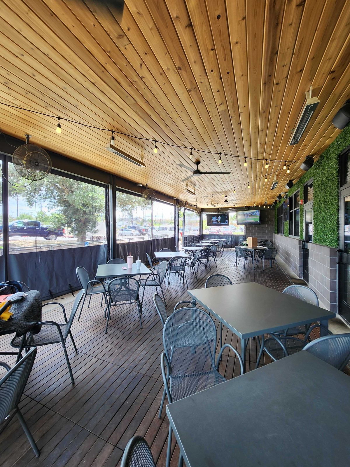 Pluckers Brooks City Base: the patio interior with the panels down and the parking lot softened through the clear