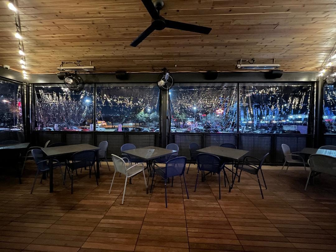 Pluckers Mesquite from inside at night: the string lights through the clear panels, tables set