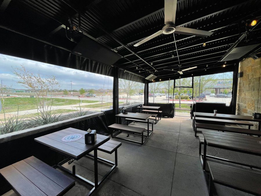 Inside Torchy's Hollyhock in Frisco: black-bordered clear panels down around the patio, picnic tables and the black ceiling