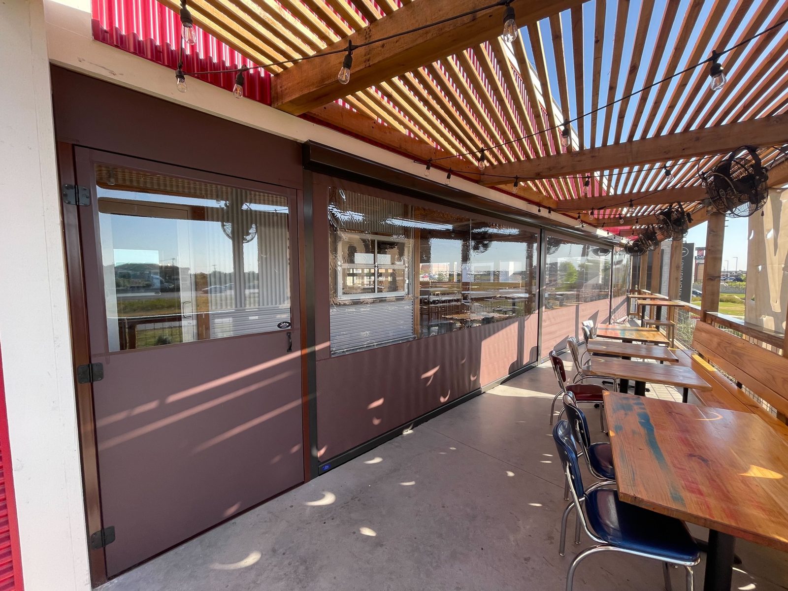 The corner where a sun shade curtain meets a clear-window curtain and one of the two steel exit doors
