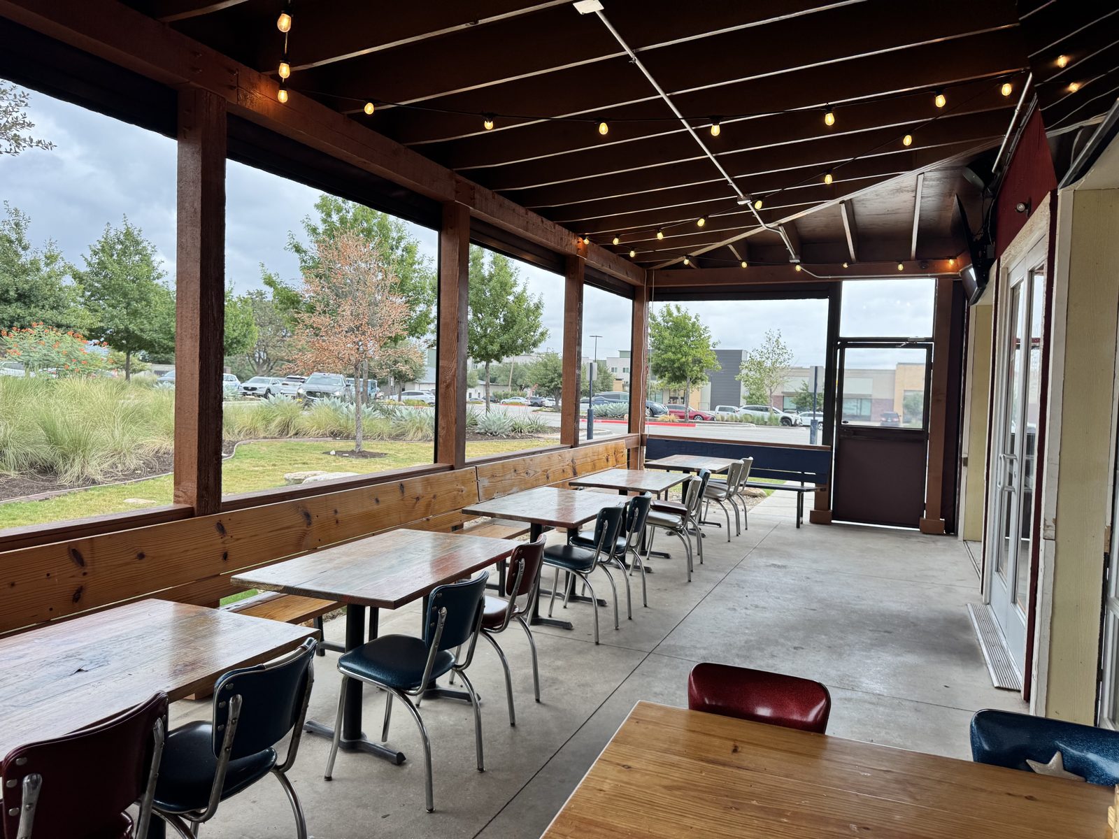 After: the same porch with the curtains rolled up into their housings, the posts and tables unchanged