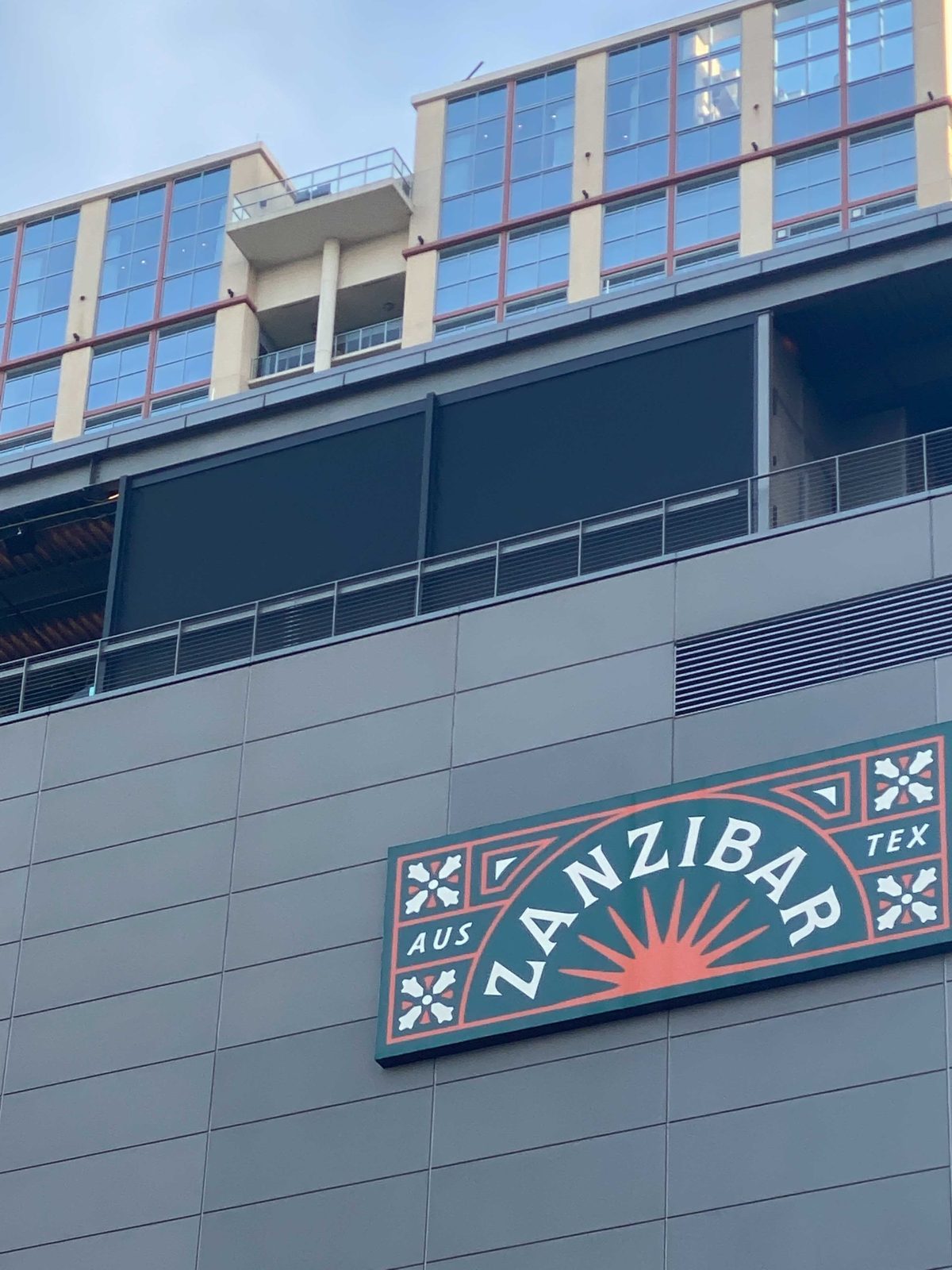 The Zanzibar sign on the hotel's street face with the black screens visible on the rooftop above