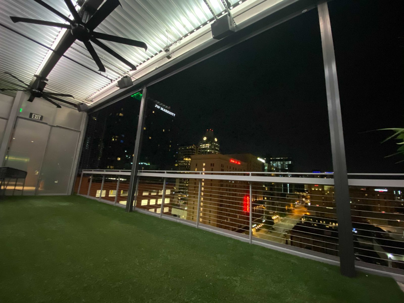 After: the screens up at night, the skyline through the cable rail and the new post at the edge of the canopy