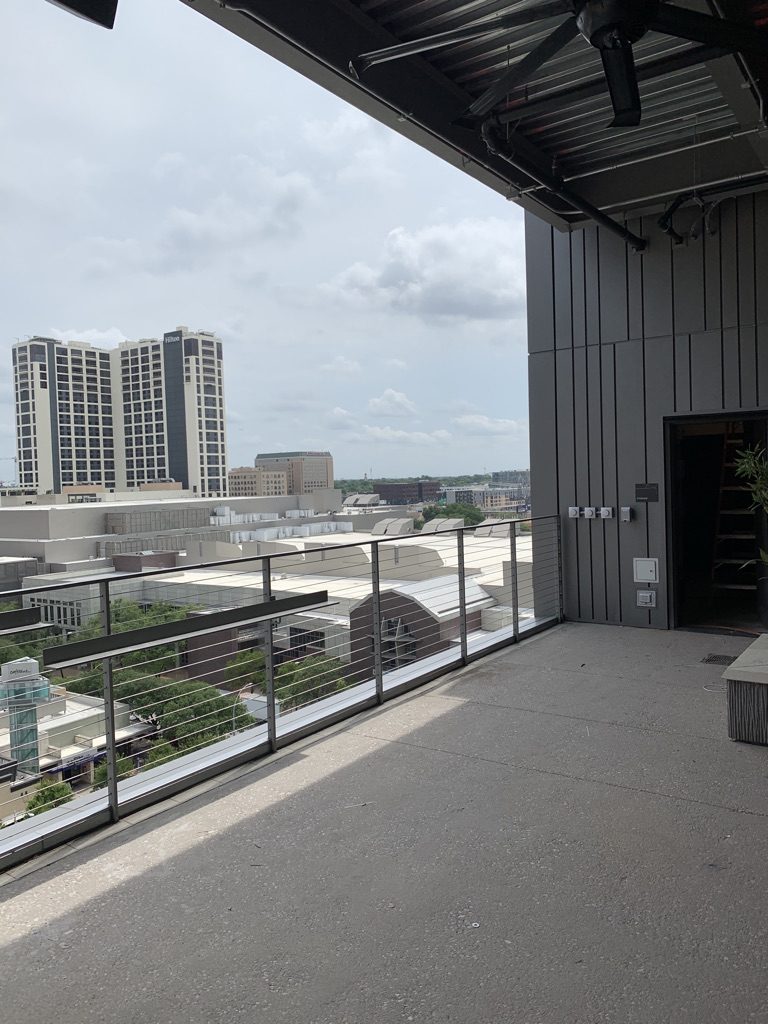 Before: the open rooftop deck in 2020, cable rail and the city beyond