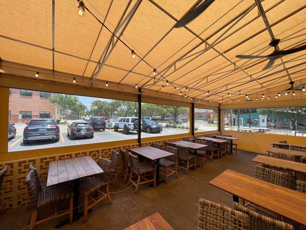 Goode Co. Kitchen & Cantina, Houston TX — inside the patio, clear windows at eye level all the way around and tables under string lights