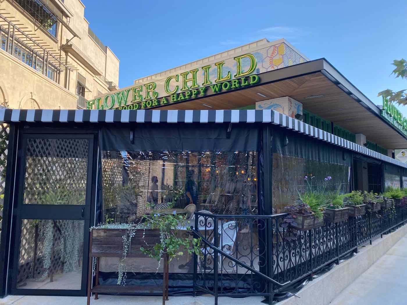 Flower Child, Austin, Texas: manual clear vinyl roll-down enclosure with black borders and a striped awning header