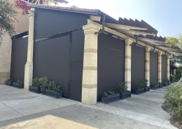 The Cheesecake Factory San Antonio – Motorized Nano 97 Sun Shades Motorized Nano 97 black sun shades installed at The Cheesecake Factory in San Antonio, Texas (La Cantera) by Southern Patio Enclosures – showing hoods, side tracks, weight bar, egress door, and custom tapered column detailing