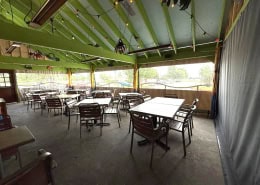 Chuy’s Mexican Food Arlington – Interior View of Manual Roll Clear Vinyl Patio Enclosure Interior view of manual roll-up clear vinyl patio enclosure at Chuy’s Mexican Food in Arlington, Texas by Southern Patio Enclosures – showing clear panels, gray solid vinyl border, large bottom border for knee wall, one black privacy panel, heaters, rope and pulley system, and festive dining tables with chairs