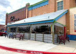 Chuy’s Mexican Food Arlington – Manual Roll Clear Vinyl Patio Enclosure Manual roll-up clear vinyl patio enclosure with gray solid vinyl border at Chuy’s Mexican Food in Arlington, Texas by Southern Patio Enclosures – showing rope and pulley system, large bottom border for knee wall, and festive outdoor patio